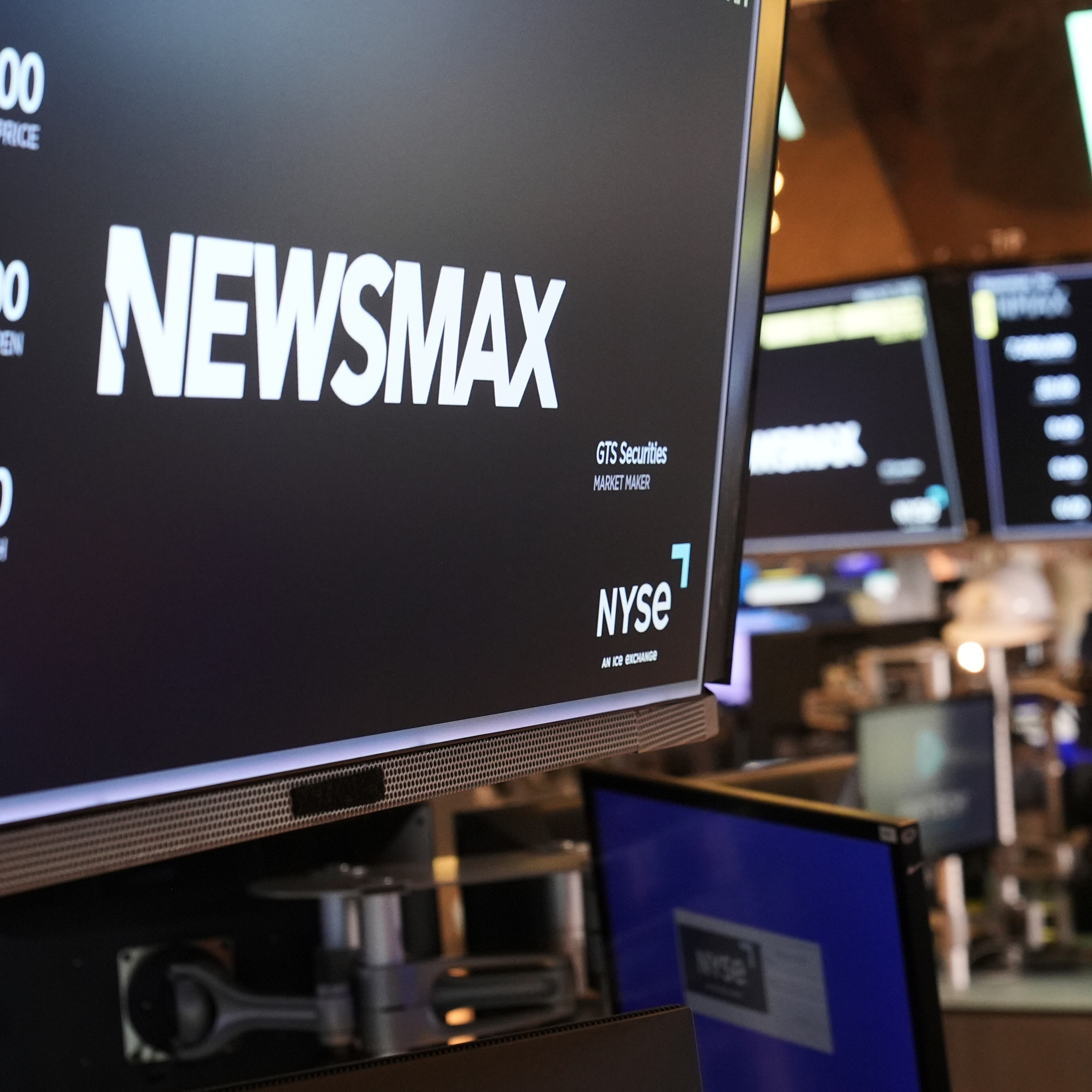 FILE - A display shows a Newsmax logo on the day of their IPO on the floor at the New York Stock Exchange in New York, March 31, 2025. (AP Photo/Seth Wenig, File)